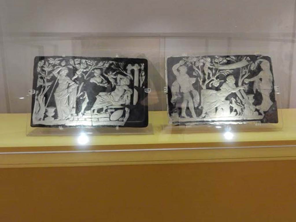 VII.16.22, Pompeii. February 2021. Glass cameo panel decorating furniture, a maenad is pouring wine into Ariadne’s cup while a Satyr dances.  
On display in Antiquarium at VIII.1.4, according to the description card, these were found in room 62. 
Photo courtesy of Fabien Bièvre-Perrin (CC BY-NC-SA).
