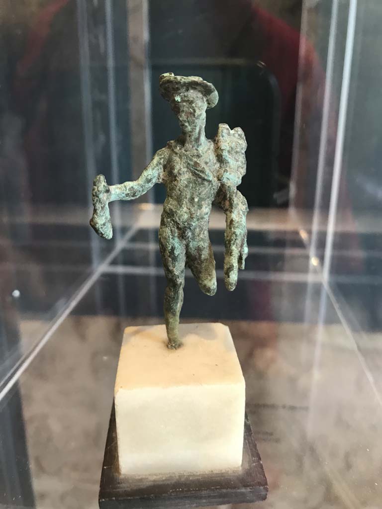 VIII.2.1 Pompeii. April 2019. 
Bronze statuette of Mercury carrying a money bag. Found in the area to the south of the House of Championnet.
Pompeii Inventory number 6331.  Photo courtesy of Rick Bauer.
According to Zanella -
This statuette was found in Room B, the triclinium on the lower floor of VIII.2.3-5 (or room belonging to VIII.2.14-16) on 9th February 1937.
See Zanella S., 2019. La caccia fu buona: Pour une histoire des fouilles à Pompéi de Titus à l’Europe. Naples : Centre Jean Bérard, (p.268).



