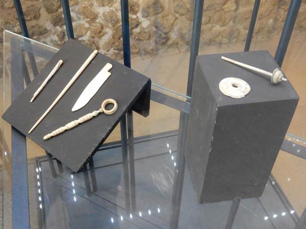 On display in Championnet complex Pompeii. May 2018. Bone items found in area to the south of the House of Championnet.
Hairpins in worked bone, used for garments or hairstyles. Pompeii inventory numbers 6313B, 6314.
Small knife. Pompeii inventory number 6329. 
Spindles with small discs for weaving. Pompeii inventory numbers 6313A, 6313D.
Photo courtesy of Buzz Ferebee.

