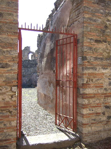 VIII.6.7 Pompeii. March 2009. Vicolo delle Pareti Rosse.  Remains of painted decoration on outside wall on east side of entrance.
