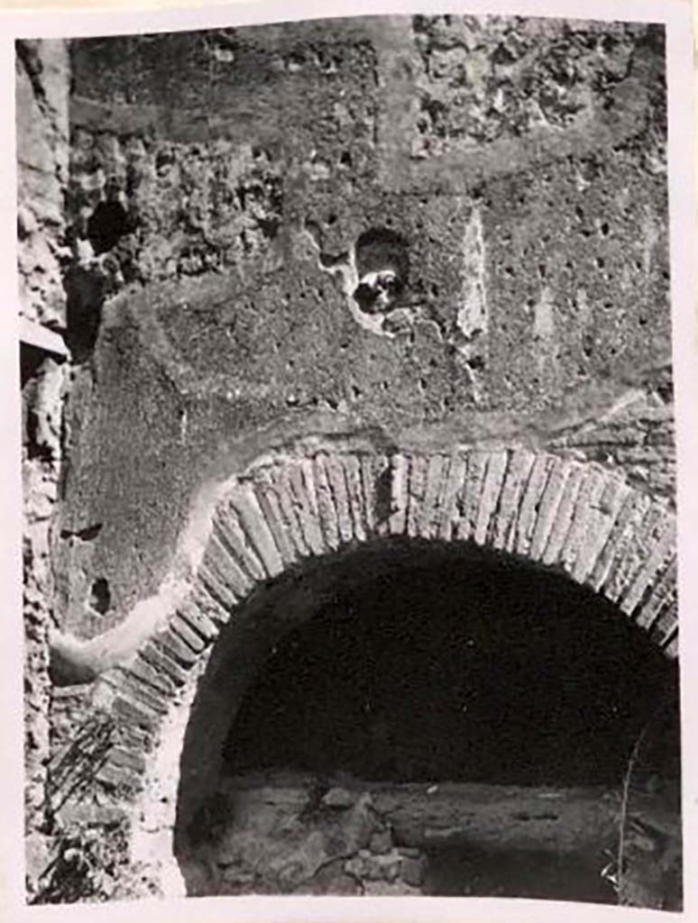 IX.1.3/ IX.1.33. Pre-1943. Brickwork and decorative plaque above oven. Photo by Tatiana Warscher.
According to Warscher –
“Above the opening of the oven, above the brickwork with the phallus, a terracotta head was embedded. 
If I am not mistaken, no-one has mentioned this.  
A. Mau cited a similar head on the hearth of the house at I.3.8, found in 1870.
Unfortunately, the head seen by Mau has gone.” 
See Warscher, T. Codex Topographicus Pompeianus, IX.1. (1943), Swedish Institute, Rome. (no.12a), p. 23.
