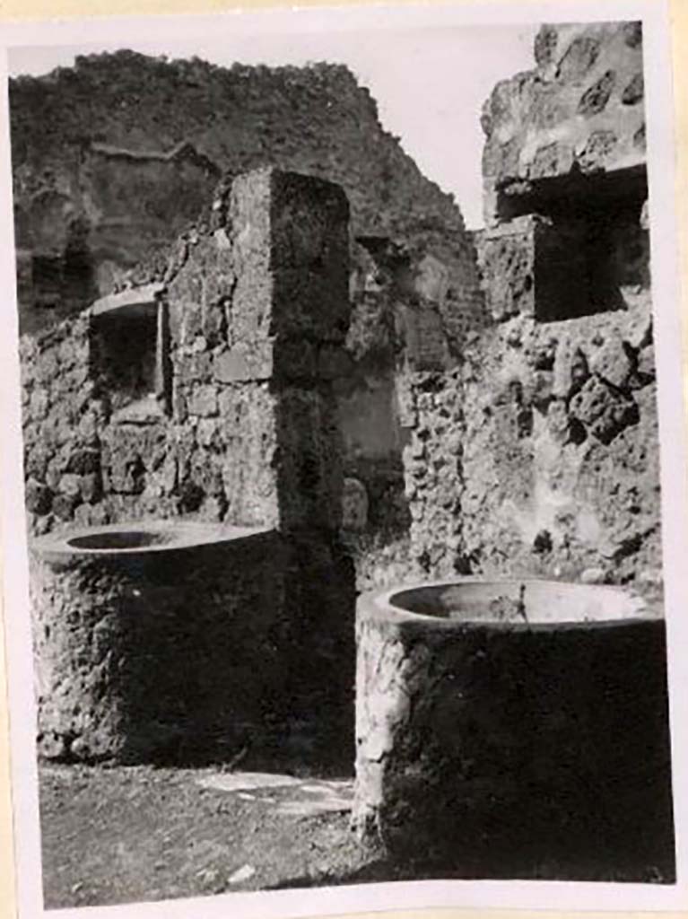 IX.1.3/33 Pompeii. Pre-1943. 
Looking south-west from oven towards two small tubs, above both were niches. Photo by Tatiana Warscher.
See Warscher, T. Codex Topographicus Pompeianus, IX.1. (1943), Swedish Institute, Rome. (no.9), p. 22.
According to Boyce –
“Against the wall facing the oven stand two small masonry basins and in the wall above each is a rectangular niche called by Fiorelli “la nicchia dei Penati”; there remains today no indication of religious purpose.”
See Boyce G. K., 1937. Corpus of the Lararia of Pompeii. Rome: MAAR 14, (379).
