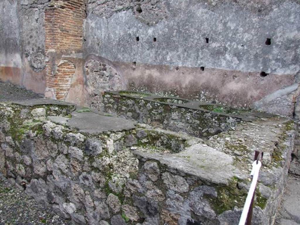 IX.1.8 Pompeii. December 2007. Counter containing remains of five urns, and holes in south wall for shelving supports.