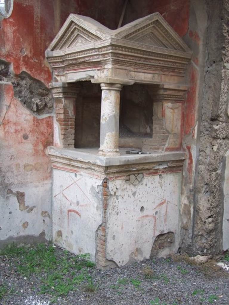 IX.1.22 Pompeii. December 2007.  Room 1, atrium with household shrine in south-east corner. According to Boyce, on the top of a high masonry podium stood the elaborately decorated aedicula.  The podium was decorated along the upper edge with a double band of painted stucco relief. There was one Doric column of heavy proportions with base and two rectangular pilasters attached to the room walls. These supported heavy entablature and cornice and a roof with two pediments. The cornices which surrounded the pediments were decorated with  uadruple bands of red and blue stucco relief.  The single column was also stucco coated and painted to imitate red and yellow marble. The walls, inside and out, were painted with decorations in red, green and yellow upon the white background; ornate portals, garlands, birds, candelabra and arabesques. Against the walls within the shrine was a low step, to serve as a pedestal for the figures of the gods.
See Boyce G. K., 1937. Corpus of the Lararia of Pompeii. Rome: MAAR 14. (p.80) 
