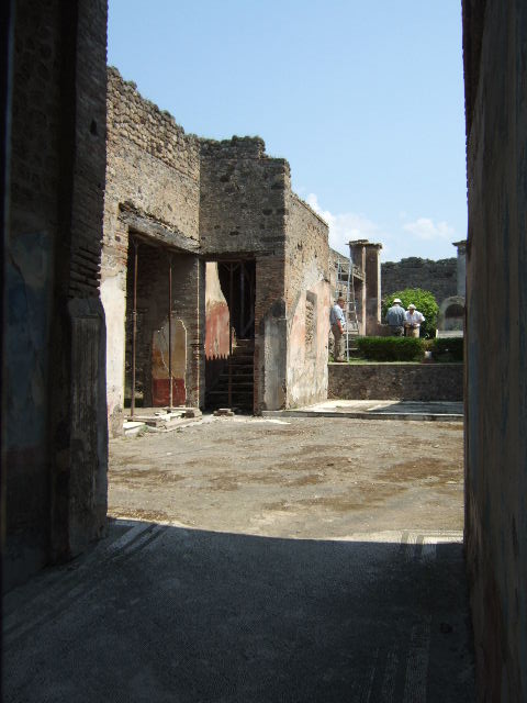 IX.3.5 Pompeii. May 2006. North-east corner of atrium. According to Dyer: “This house appeared to have been under repair at the time of the eruption; at least we cannot in any other way account for the rough state in which the impluvium or water-basin, in the atrium was found.  It was no doubt intended to be lined with marble: in its present state it forms a strong contrast with the elegance of the rest of the atrium. This has a pavement of white mosaic; the lower part of the walls are painted in imitation of variously-coloured marbles; above, the walls are blue and ornamented with grotesques; the whole surmounted by a frieze of gilt stucco, many fragments of which were found during the excavation. The bed-chambers and other rooms which surround the atrium contained several good paintings, some of which have been removed to Naples Museum.
See Dyer, T., 1867. The Ruins of Pompeii. London: Bell and Daldy. (p.84)
