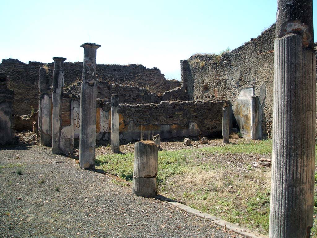IX.5.14 Pompeii. May 2005. Looking south-west across portico of two-sided peristyle k.
According to Jashemski, the portico of the garden was entered directly from the atrium. There was no tablinum.
The portico was supported by four white stuccoed columns on the east, and on the south by six somewhat lower columns.
The two rooms on the east, described by Eschebach as exedra or triclinia, had a good view of the garden.
See Jashemski, W. F., 1993. The Gardens of Pompeii, Volume II: Appendices. New York: Caratzas. (p.237)  
