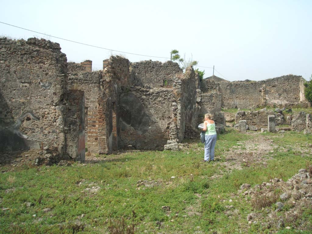IX.6.g Pompeii. May 2005. West side of IX.6.g in foreground, looking west towards remains of IX.6.4, in upper right.
South wall of garden area of IX.6.4, approximately where the figure is standing.
