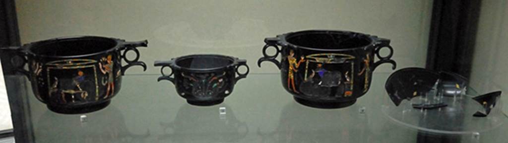 Villa San Marco, Stabiae. Found in room 37, May 1954, near the south east wall. 
Three obsidian Skyphii (cups) with Egyptian scenes inlaid in gold and mosaic and fragments of a phiale (broad flat container) with Nilotic scenes.
From left to right they are Skyphos A, C, B and the phiale.
Photographed December 2007 in Naples Archaeological Museum. Inventory numbers 294471, 294472, 294473 and 294474.
See Barbet A. (a cura di), 1999. La Villa San Marco di Stabia: Illustrazioni 1. Roma, L’Erma di Bretschneider. Figs. 717 to 723.
See Elia O., 1957. Le coppe ialine di Stabia, in BdA, 42. pp. 97-103.
