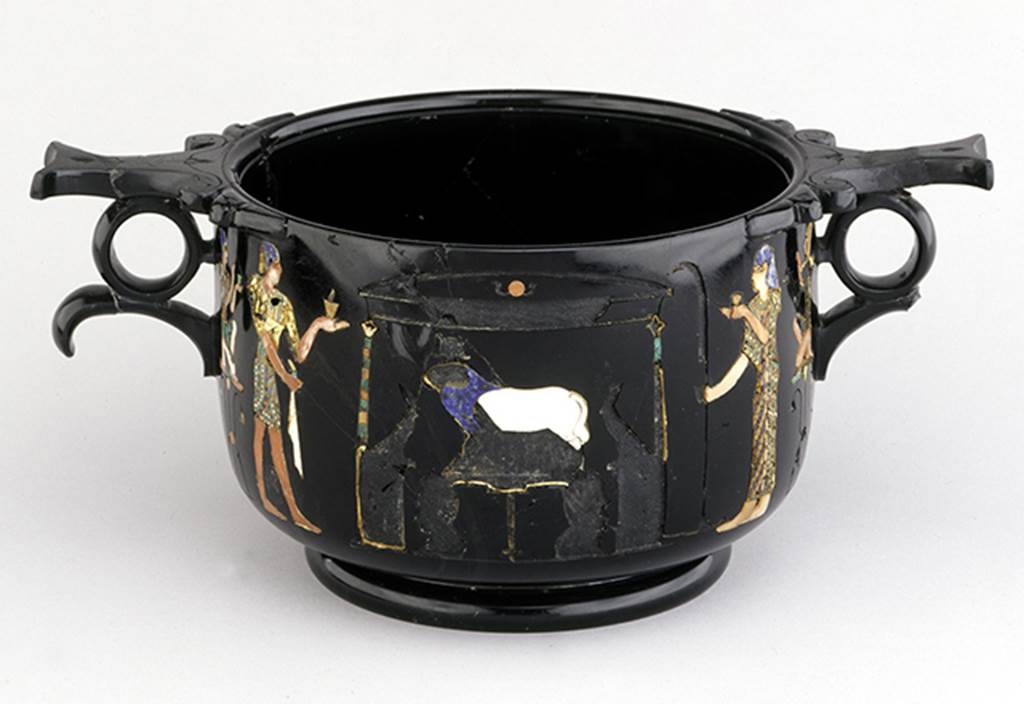 Castellammare di Stabia, Villa San Marco, Found May 1954, room 37, near the south east wall. Side of obsidian skyphos (cup) B with Egyptian scenes of ram worship inlaid in gold and mosaic. Now in Naples Archaeological Museum.  Inventory number  294473.
