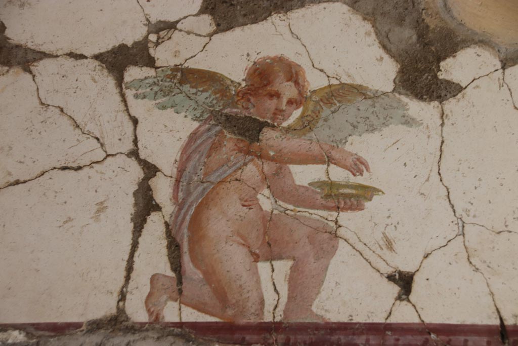 Villa San Marco, Stabiae, October 2022.  
Room 30, detail of kneeling Eros holding a dish, from east wall above doorway to room 50, in north-east corner.  
Photo courtesy of Klaus Heese.
