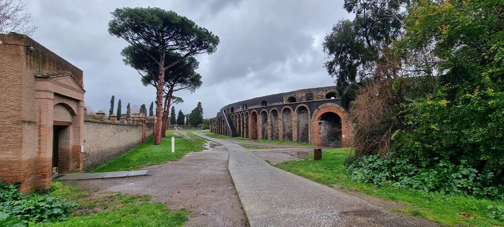 Piazzale Anfiteatro. January 2023. 
Looking north across Piazza/Viale Anfiteatro, with Grand Palaestra, on left, and Amphitheatre, on right. Photo courtesy of Miriam Colomer.
