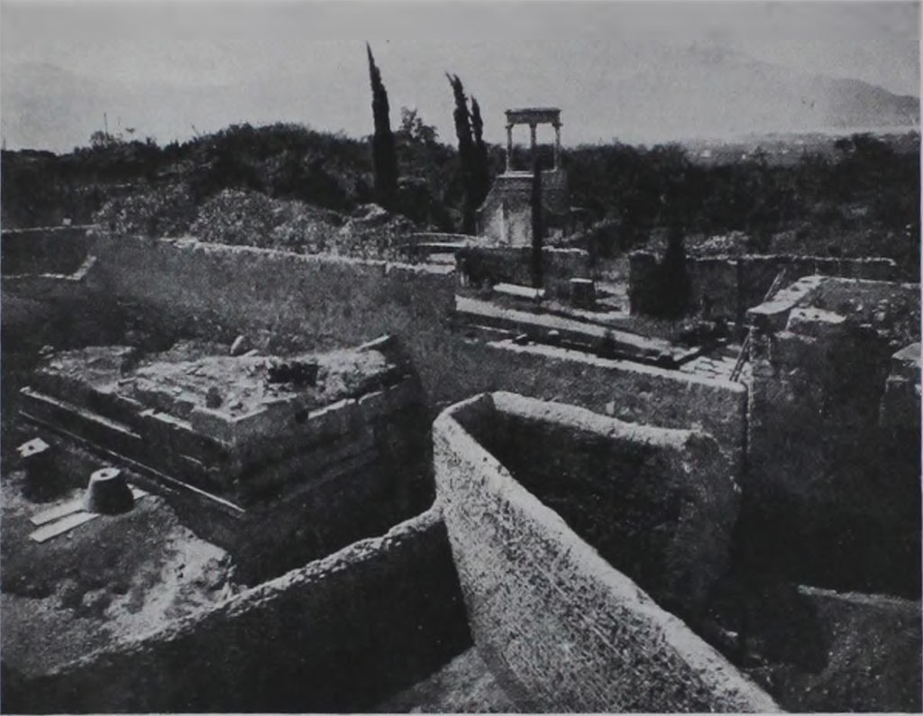 HGE04 Pompeii. 1933-5. View of rear of tomb during excavations showing also the cone found by Maiuri.
According to Kockel in 1933/35, A. Maiuri excavated the entire area between the city wall and the Villa delle Colonne a mosaico, completely exposing North 4 as well. 
To the north of the base he found a cone and a Corinthian capital to match.
See Kockel V., 1983. Die Grabbauten vor dem Herkulaner Tor in Pompeji. Mainz: von Zabern, p. 122. 
See Notizie degli Scavi di Antichit, 1943, p. 301, fig. 17.

