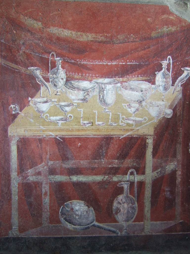 VGJ Pompeii.  May 2006.  Inner side of north wall of tomb.  Painting of the silver flasks, cups, bowls, dishes, ladles used at the funeral feast.  These are on a yellow table with a dark red background.
