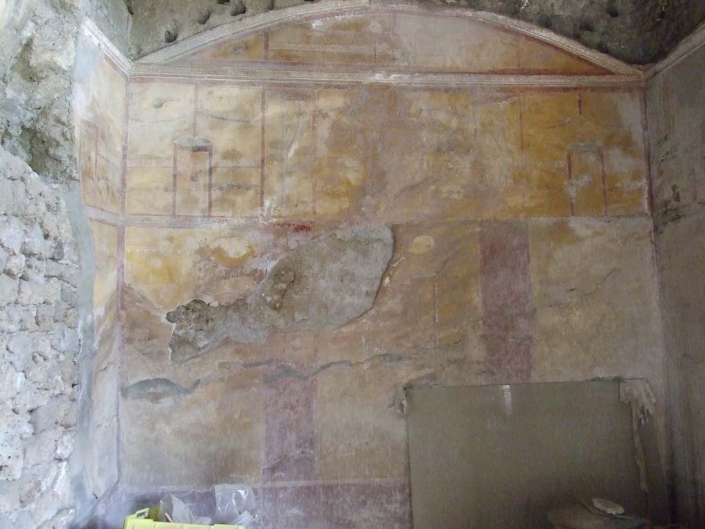 I.9.3 Pompeii. March 2009. Room 10, looking towards the east wall.
According to PPM, on the left can be seen a hole made by the ancient searchers on the north wall. 
The middle zone of the east wall was yellow, with a central aedicula which contained a painting of Adone ferito (now faded).
The upper area was also yellow with a painting of Venus Pompeiana in the centre aedicula.
In the side panels of the upper area, were hanging buckets separated by architectural views, garlands, borders with “carpet” pattern, and dolphins in the corners, and holes made by the support beams for the vaulted ceiling.  
