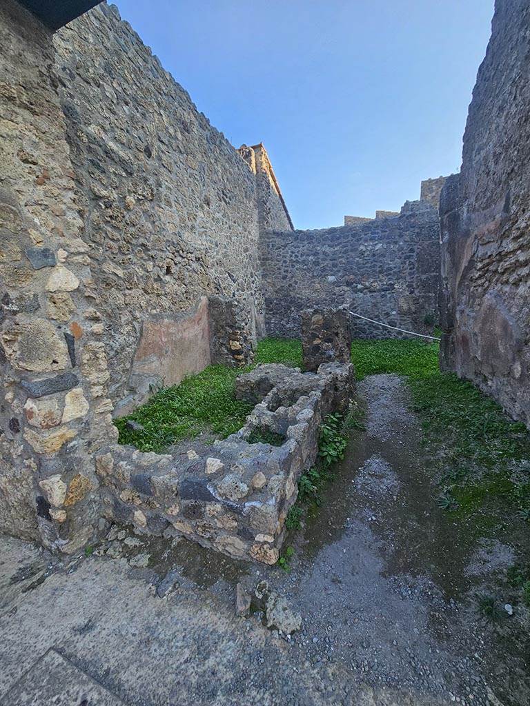 I.10.2, Pompeii. November 2024. Looking south-east across remains of podium/counter. 
In the south-east corner, at the rear of the bar-room, is a doorway to a rear-room. Photo courtesy of Annette Haug.
