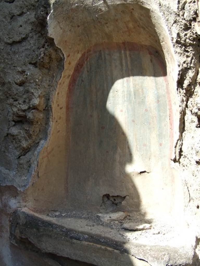 V.4.13 Pompeii.  March 2009.  Garden.  Lararium niche in north west corner.  Remains of painting in niche. Detail of west side.  The niche was painted with red and yellow stylised flowers and yellow stars with red centres.
See Giacobello, F., 2008. Larari Pompeiani: Iconografia e culto dei Lari in ambito domestico.  Milano: LED Edizioni.  (p.268).
