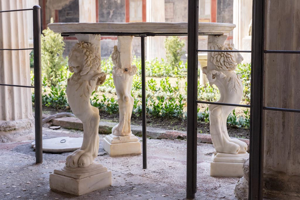 VI.15.1 Pompeii. March 2023. 
Table with three lion legs in peristyle, looking south-west from east portico. Photo courtesy of Johannes Eber.

