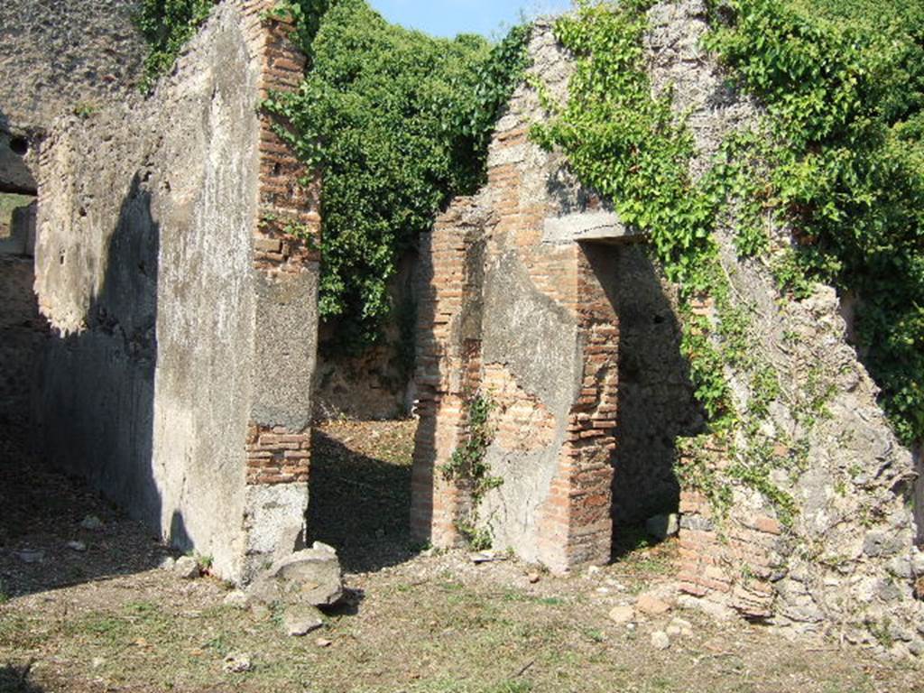 VI.15.20 Pompeii. September 2005. Looking north-east from atrium towards doorways to corridor to kitchen, left, and oecus, centre. According to Hobson, Reg. VI had two upper storey latrines that still had visible signs of the latrine above the ground floor level, these were in VI.15.20 and VI.15.22. See Hobson, B., 2009. Latrinae et foricae: Toilets in the Roman World. London; Duckworth. (p.75)
According to Eschebach, the corridor on the north side of the atrium led to the kitchen and latrine which had a downpipe from the upper floor. See Eschebach, L., 1993. Gebäudeverzeichnis und Stadtplan der antiken Stadt Pompeji. Köln: Böhlau. (p.223)
According to NdS, only the lower part of the walls of the oecus were faced with white plaster, partitioned by black lines. In the south wall was a small niche. See Notizie degli Scavi di Antichità, June 1897, (p.275)
In the room to the north of the tablinum, the doorway on the right of this photo, a pile of lime prepared for work was found, together with some tiles. (p.274)