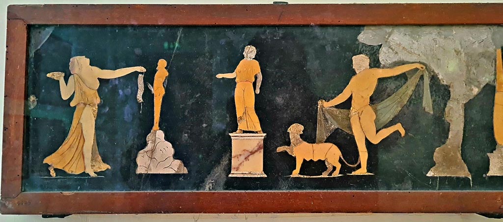 VII.4.31/51 Pompeii. 
Found in tablinum on 22nd May 1845. Dionysian scene in coloured marble. Photo courtesy of Giuseppe Ciaramella. September 2024.
Now in Naples Archaeological Museum. Inventory number 9979.  
According to information card –
Dionysian scene. Slate wall panel with polychrome marble inlay work.
A statue on a pedestal is depicted in the centre of the scene; Dionysus, dressed in a cloak, is dancing on the right, preceded by a panther; on the left, a Maenad, who is also dancing, brings offerings to a statue of Priapus, placed on a rock. (Third quarter of the Ist century AD).
(Scena dionisiaci. Panello parietale di ardesia con intarsia marmorei policromi.
La scena raffigura, al centro, una statua su piedistallo; Dioniso con mantello danza, da destra, preceduto da una pantera; mentre da sinistra, una Menade pure danzante reca offerte alla statua di Priapo, posto su una roccia. Terzo quarto del I secolo d.C.)

