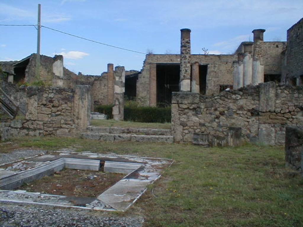 VII.7.5 Pompeii. September 2004. Looking north-west across atrium (b), towards steps to peristyle (l).
Taken from the gate of VII.7.4
According to Jashemski, this house attached to the preceding one, had a peristyle garden enclosed on four sides by a portico.
This was supported by twelve columns, red at the bottom, white and fluted above.
In the middle of the garden was a rectangular pool painted blue on the inside.
There was no tablinum in this house and the peristyle was reached by two steps from the atrium.
The exedra (u) on the north had a fine view across the garden.
See Jashemski, W. F., 1993. The Gardens of Pompeii, Volume II: Appendices. New York: Caratzas. (p.186 and fig.219, the peristyle garden)