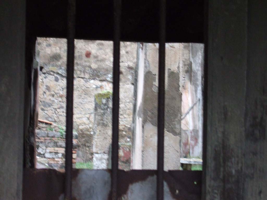 VII.12.28 Pompeii. December 2005. Looking north through doorway.
According to Pagano –
“Una scala di legno dava accesso al piano superiore, e questo slargavasi sulla via mediante un tavolato sorretto da travi e fornito di finestre che guardavano nella strada. Nel restaurarsi questo balcone, si era avuto mente a riprodurre con esattezza i legni che prima vi erando adoperati per sostenerio.

Entrando nella casa trovasi a sinistra la scalinata di legno che metteva al piano superiore. Viene in seguito un piccolo atrio dove ammirasi una graziosa fontana formata da un Puttino che regge colla sinistra una piccola colomba attualmente rotta, da cui sortiva un getto d’acqua che cadeva in una vaschetta. 
Al di sotto del tavolino che vedesi alle spalle del Puttino, si osservano quattro chiavi di bronzo, per somministrare l’acqua in diversi punti della casa.
Il tablino ha un quadretto sulla parete a sinistra, che esprime Alceste ed Admete, allegoria dell’amor coniugale.”
See Pagano, N. (1881).Guida di Pompei, ed.9. (p.49-50).
(translation –
"A wooden staircase gave access to the upper floor, and this opened up onto the street with a floor supported by beams and provided with windows looking into the street. In restoring this balcony, it had been thought to reproduce exactly the woods that had previously been used to support it.

Entering the house, on the left we find the wooden staircase to the upper floor. Then came a small atrium where one could admire a pretty fountain formed by a Puttino/small boy/cherub that held in his left hand, a small dove (or shell) currently broken, from which a jet of water would have fallen into a tub. 

Below the marble table we can see behind the Puttino, four bronze keys were observed, to administer water at different points of the house. 
The tablinum had a picture on the left wall, showing Alcestis and Admetus, an allegory of marital love.")

