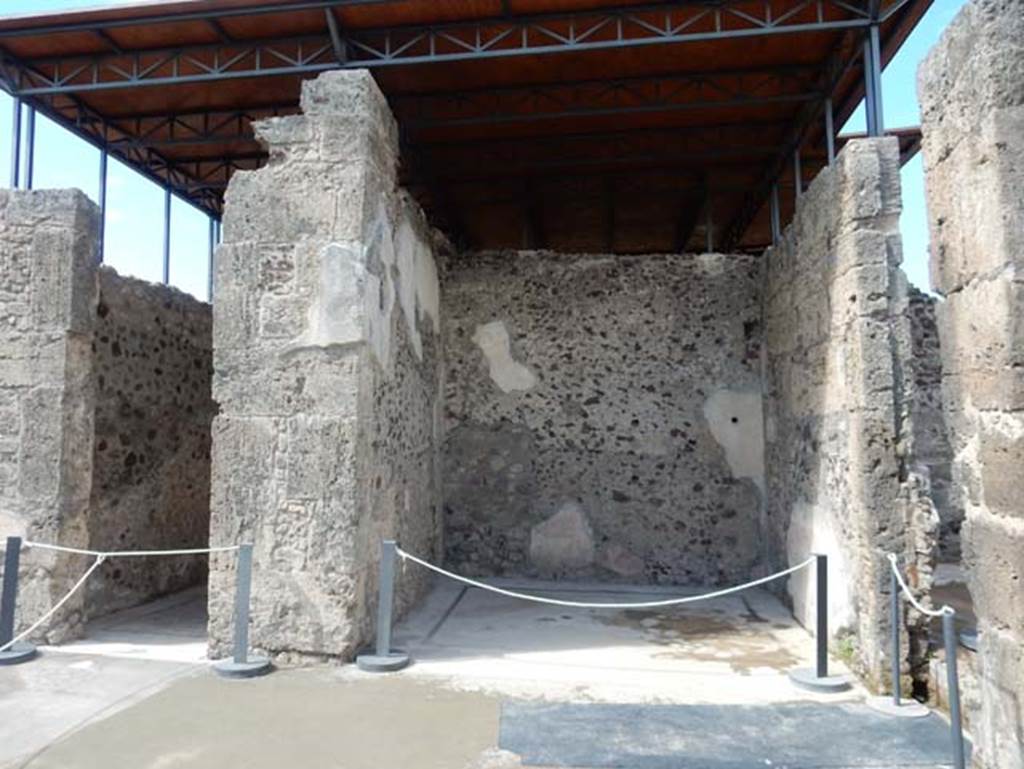 VII.15.2 Pompeii. May 2018.West side of atrium, with doorway to cubiculum, on left, and west ala, in centre. Photo courtesy of Buzz Ferebee.
VII.15.2 Pompeii. May 2018.West side of atrium, with doorway to cubiculum, on left, and west ala, in centre.
Photo courtesy of Buzz Ferebee.
According to Sogliano, seen in the west ala –
“A crowned cupid, and with green wings, playing the flute, leaning on a dolphin, throwing him into the sea.” (Evanescent)
(Eros coronato e con ali verde, suonante il flauto, appoggiato ad un delfino, che si precipita nel mare. (Evanescente)
(Bull.Inst, 1872, p.173, Fiorelli, Scavi di Pompei, p.124, no.199; Descr.Pomp, (p.305).
See Sogliano, A., 1879. Le pitture murali campane scoverte negli anni 1867-79. Napoli: Giannini. (p.62, no.355).
“Robust figure of a God, standing, turn to the left, and, apparently, naked: leaning with the left hand onto a trunk of a bare tree that forks into two branches, and in the right hand has something like a disc or globe, which you can not recognize with confidence.”
(Robusta figura di un Dio in piedi, volta a sinistra, e, a quel che pare, nuda: si appoggia con la sinistra a un tronco di albero sfrondato che si biforca in due rami, e nella destra ha come un disco o globo, che non si puo riconoscere con sicurezza.) (Bull.Inst, 1872, p.173)
See Sogliano, A., 1879. Le pitture murali campane scoverte negli anni 1867-79. Napoli: Giannini. (p.127, no.619)
“Traces of female figure on foot, with a branch in her left hand.”
(Tracce di figura muliebre in piedi con ramo (?) nel braccio sinistra.)
(Bull.Inst, 1872, p.173)
See Sogliano, A., 1879. Le pitture murali campane scoverte negli anni 1867-79. Napoli: Giannini. (p.127, no.620)
According to PPM –
“In the centre of the west wall was located a female figure with a branch in her left hand, while in the north panel was a medallion with blue background”.
See Carratelli, G. P., 1990-2003. Pompei: Pitture e Mosaici: Vol. VII. Roma: Istituto della enciclopedia italiana, (p.730).