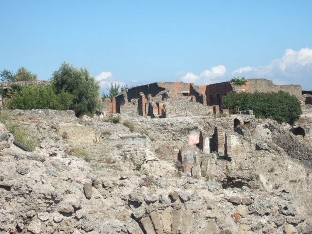 VIII.2.16 Pompeii. September 2004. Looking east towards rear of house at top of slope, and lower levels. Photo taken from exit of site. 

According to PPM  VIII.2.14-16 (p.74 and 75)  regarding rooms on lower levels -
and those (rooms) on the west side belonged in reality to the house at nos. 3-5.
And -
On the lower level, and reachable by stairs towards the west, were rooms 10-13, which had mosaic flooring and remains of paintings of mediocre quality.
The rooms (14-22), about 3m higher than the rooms 10-13, were probably reachable from the house at no. 3, even if built in the same building phase.
(For photos taken of rooms 16 and 22, see VIII.2.3, pt.2). 
See Carratelli, G. P., 1990-2003. Pompei: Pitture e Mosaici. VIII. (8). Roma: Istituto della enciclopedia italiana, (p. 74 and 75). 

According to Boyce, in a kind of cave beneath the court located behind the large atrium of number 16, on the extreme edge of the slope was a sacrarium of peculiar nature.
Against the rear wall of a narrow passage was built a masonry seat.
In the wall above it, a vaulted opening led into a small cell hewn out of the rock, with its floor 0.50m below that of the outer passage.
A second masonry seat was built within the cell, back to back with that in the outer passage.
The only means of entrance into this inner chamber appeared to have been over these two seats and through the small opening above them.
Within the cella stood a rectangular masonry altar and upon the altar lay a small terracotta altar, a marble ball, and two lamps decorated with reliefs.
One of the lamps was decorated with the relief of Jupiter, the other of a rose.
See Notizie degli Scavi di Antichit, 1890, 290.
See Boyce G. K., 1937. Corpus of the Lararia of Pompeii. Rome: MAAR 14. (p.74, no.344) 
See Giacobello, F., 2008. Larari Pompeiani: Iconografia e culto dei Lari in ambito domestico. Milano: LED Edizioni. (p.246)


