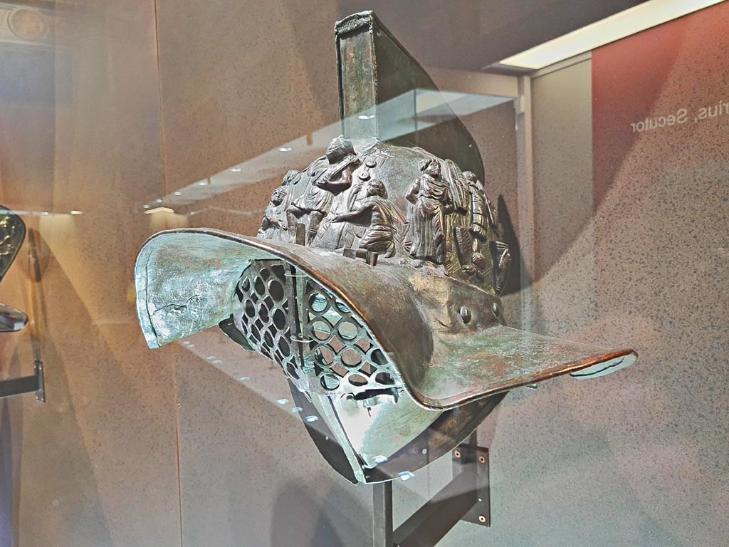 VIII.7.16 Pompeii. Photo taken May 2021, in Naples Archaeological Museum, inv. 5674.
Murmillo gladiator’s helmet, with personification of Rome, Barbarian captives, trophies and Victories.
(Side 1). Photo courtesy of Giuseppe Ciaramella.