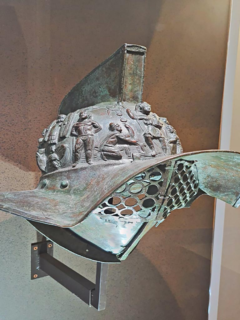 VIII.7.16 Pompeii. Photo taken May 2021, in Naples Archaeological Museum, inv. 5674.
Murmillo gladiator’s helmet, with personification of Rome, Barbarian captives, trophies and Victories.
(Side 2). Photo courtesy of Giuseppe Ciaramella.