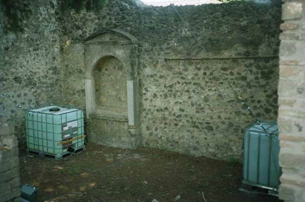 VIII.7.28 Pompeii. July 2010. Irregular shaped sacred room. North wall. Mau describes a sacred room that seems to have been used for secret ceremonies. It was entered from the colonnade by a narrow door which could be securely fastened. On the north side is a niche that apparently formed part of a small shrine. The water filled plastic bottles are stabilisers for the lighting towers used in the large theatre. See Mau, A., 1907, translated by Kelsey F. W. Pompeii: Its Life and Art. New York: Macmillan. (Page 181). Photo courtesy of Rick Bauer.