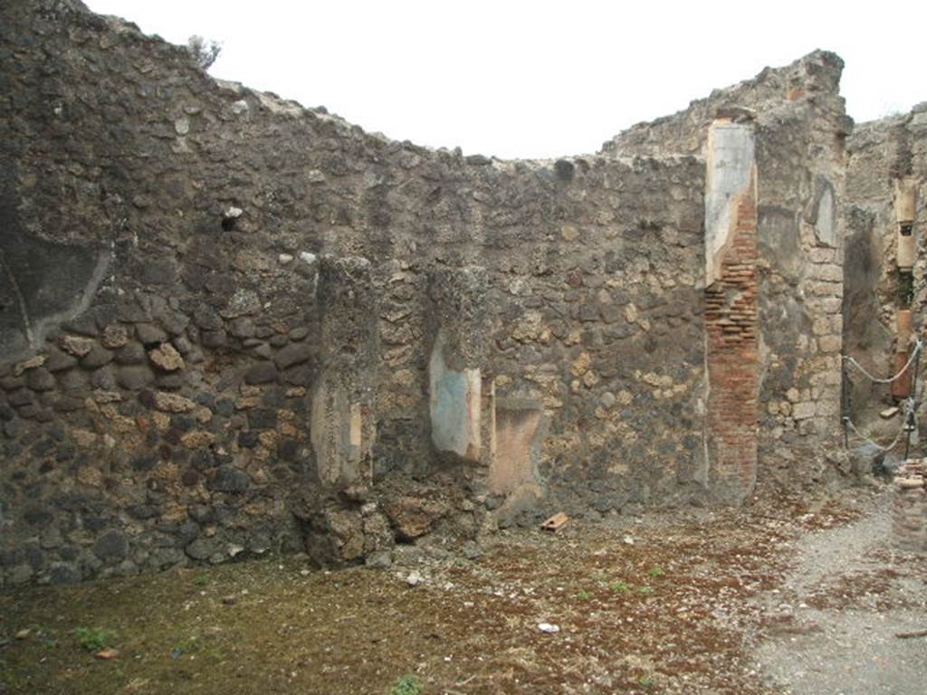 IX.2.27 Pompeii. May 2005.
Remains of a shrine on the west wall of the peristyle.
The doorway to the kitchen and latrine by rear entrance at IX.2.28 is on the right.