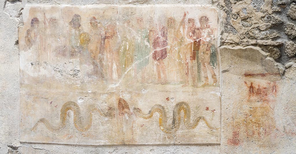 IX.12.6 Pompeii. July 2024.
Room “n1”, detail of lararium painting on west wall, on the right is the preparatory sketch?. Photo courtesy of Johannes Eber.
Lararium painting showing Hercules being presented to twelve gods in the upper part.
Underneath are two serpents approaching an altar.
To the right are the remains of a possible preparatory sketch for a lararium painting?