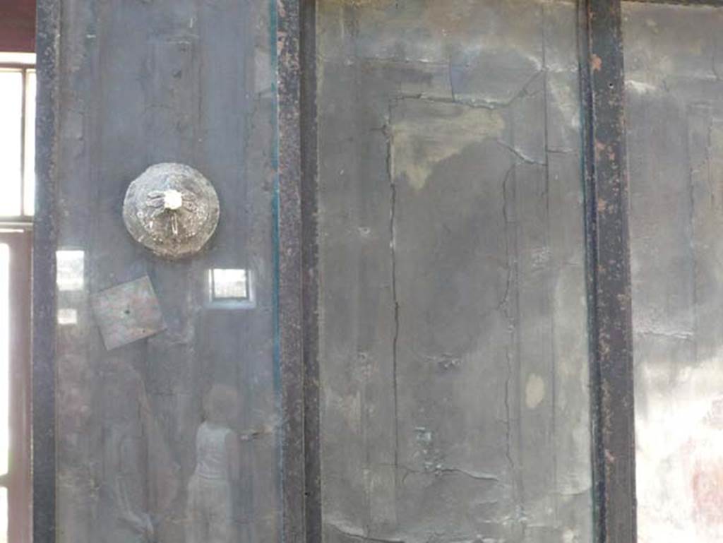 III.11 Herculaneum. May 2009. Room 6, detail of wooden screen at north end. Photo courtesy of Buzz Ferebee.
According to Maiuri,the wooden leaves, extracted from the hardened mud, swing once more upon their ancient hinges and the bronze lamp supports, in the form of ship’s stern ornaments, are fixed once more in the upright posts.
See Maiuri, Amedeo, (1977). Herculaneum. 7th English ed, of Guide books to the Museums Galleries and Monuments of Italy, No.53 (p.33).
