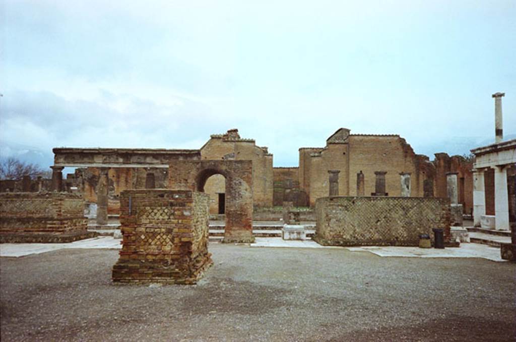 Arched monument at south end of Forum. May 2010. Photo courtesy of Rick Bauer. According to Mau, these four monuments were of the imperial family. The arched monument was probably the pedestal for a colossal statue of Augustus. The wide statue base on the right was for a colossal equestrian statue of Claudius. The wide base on the left was for a colossal standing statue of Agrippina. The smaller base (the nearest in this photograph) was for the smaller equestrian statue of Nero. None of these statues survive. See Mau, A., 1907, translated by Kelsey F. W. Pompeii: Its Life and Art. New York: Macmillan. (Page 47, Plan II).