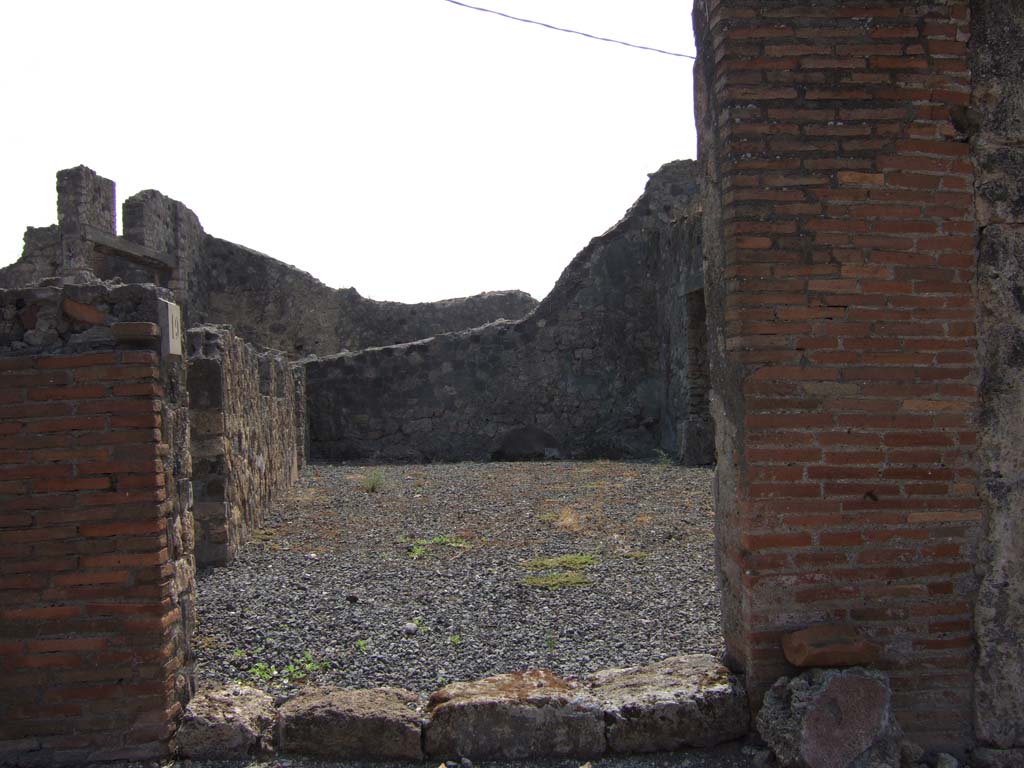 VII.7.19 Pompeii. September 2005. Looking south from entrance directly into atrium.
According to Eschebach, in the middle of the south wall would have been a lararium.
On the left, east side, can be seen doorways to an oecus with stairs to upper floor, and a triclinium fenestratum.
See Eschebach, L., 1993. Gebäudeverzeichnis und Stadtplan der antiken Stadt Pompeji. Köln: Böhlau. (p.302)
According to Boyce –
in the centre of the south wall of the large central room was a rectangular niche (h.0.48, w.0.45, d.0.22, h. above floor 1.65); 
in the west wall, near the floor, was an arched niche (h.0.92, w.0.55, d.0.20, h. above floor 0.55).
The latter was called the lararium by Fiorelli, although the former was more like the usual shrine.
See Boyce G. K., 1937. Corpus of the Lararia of Pompeii. Rome: MAAR 14. (p.68, no.300) 

