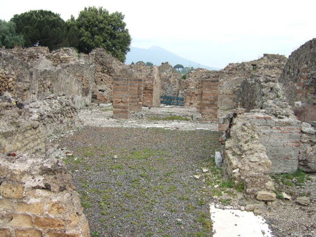 VIII.2.29 Pompeii. September 2005. Looking north across tablinum to atrium and entrance doorway.
In the north-west corner of the atrium would have been a masonry lararium, (in the area to the left of the brick pilasters).
According to Boyce, this lararium was later in date than the stucco of the walls of the room. The walls were in the IVth Style.
Around the base of the lararium ran a dado of marble.
In this corner of the atrium the black border in the mosaic pavement was made to run around the two sides of the podium.
This marked its position.
According to Mau, some other object stood here before the construction of the lararium.
These would have been either the arca for the money, or a smaller and more modest lararium, which was then enlarged.
See Notizie degli Scavi di Antichità, 1883, 135. Bull. Inst, 1885, pp.88, 93.
See Boyce G. K., 1937. Corpus of the Lararia of Pompeii. Rome: MAAR 14. (p.74, no. 346) 
According to Giacobello, only the podium survives of the aedicula in the north-west corner of the atrium.
See Giacobello, F., 2008. Larari Pompeiani: Iconografia e culto dei Lari in ambito domestico.  Milano: LED Edizioni. (p.247, no.A32)


