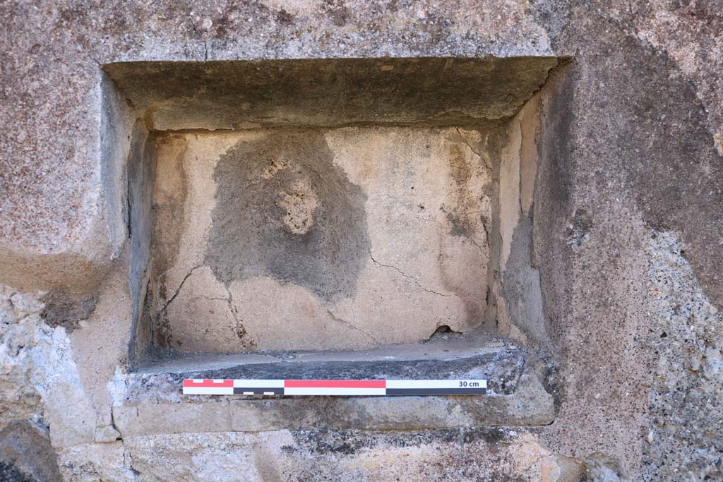 IX.2.7 Pompeii. December 2018.  Detail of niche in south wall of shop room. Photo courtesy of Aude Durand.
According to Boyce –
In the south wall is a rectangular niche (h.0.32, w.0.44, d.0.22, h. above floor 1.45). 
The excavation report stated this was a lararium. He gave the reference Bull. Arch. Nap., N.S.1, 1853, 25.
See Boyce G. K., 1937. Corpus of the Lararia of Pompeii. Rome: MAAR 14. (p. 80, no. 392).


