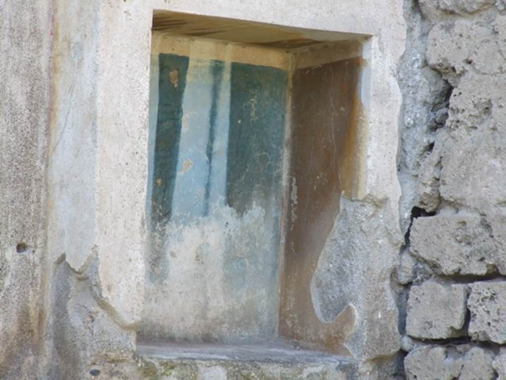 III.4.1 Pompeii. March 2009. Rectangular niche on west wall, with yellow and blue walls inside the niche.
According to Boyce –
In the west wall is a rectangular niche (h.0.58, w.0.34, d.0.25, h. above floor 1.20) with an aedicula façade painted on the wall around it. 
Two pilasters supported a white architrave and a blue pediment which was ornamented with a white disc in the centre and surrounded by white cornices.  
The side walls within the niche were yellow, the back wall was blue, and the corners white.
See Boyce G. K., 1937. Corpus of the Lararia of Pompeii. Rome: MAAR 14. (p.30, No.65, Pl.1, 6)


