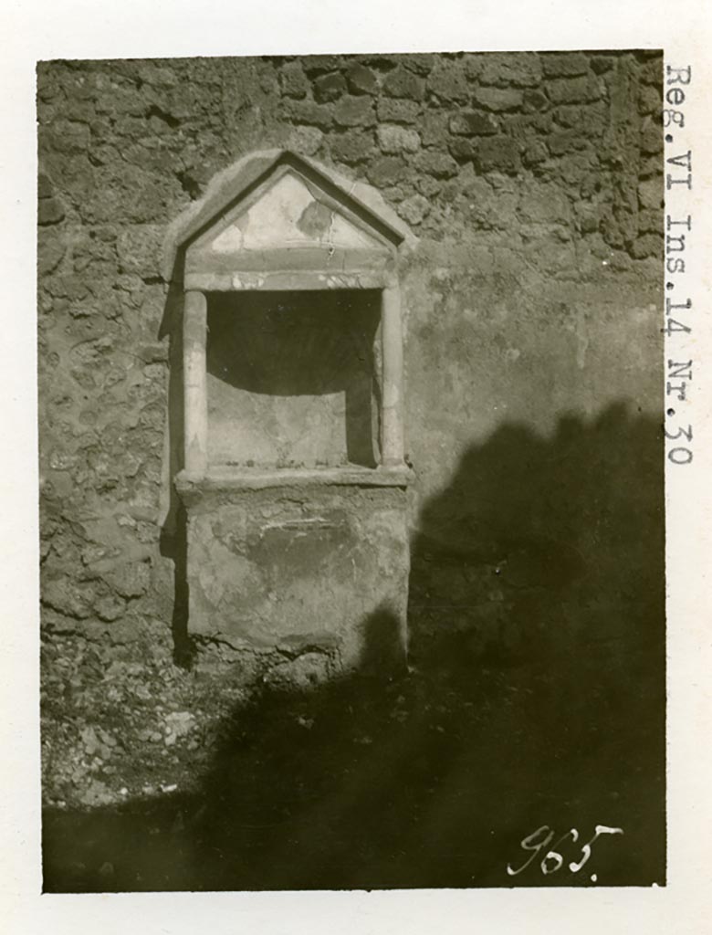 VI.14.30 Pompeii. Pre-1937-39. Aedicula against east wall of garden. 
Photo courtesy of American Academy in Rome, Photographic Archive. Warsher collection no. 965.

According to Boyce, against the east wall of the garden stands an aedicula (h.2.10). 
Above a solid base (0.88 by 0.28, h.0.85), two columns without capitals (h.0.72) support a pediment. 
In the tympanum is painted a large aquatic bird of reddish colour with wings spread.
It stands upon a black cloth, across its wings lies a black cord ending in a bow-knot, on each side of the bird stands a green marine goat.
The base of the aedicula is black, adorned with a painted garland. 
The rear wall within the shrine is hollowed out in the form of a seashell and painted in imitation of one.
In the south wall of the same garden is a niche with projecting floor and vaulted ceiling.
Its walls are adorned with painted plants, flowers and birds.
We can only speculate on the purpose of this niche. 
Presumably the aedicula is the lararium, the niche probably contained a figure of primarily decorative character.
See Boyce G. K., 1937. Corpus of the Lararia of Pompeii. Rome: MAAR 14. (p.53, no.203, and Pl. 35,1)

According to Giacobello, the painted decoration on the aedicula and architecture has disappeared, leaving only the stone podium and the niche. 
The wall was decorated with a rich garden painting.
Regarding the niche on the south wall of garden, originally painted with flowers, plants and birds, today disappeared, only the red plaster remains.
See Giacobello, F., 2008. Larari Pompeiani: Iconografia e culto dei Lari in ambito domestico. Milano: LED Edizioni. (p.275 no.V54)


