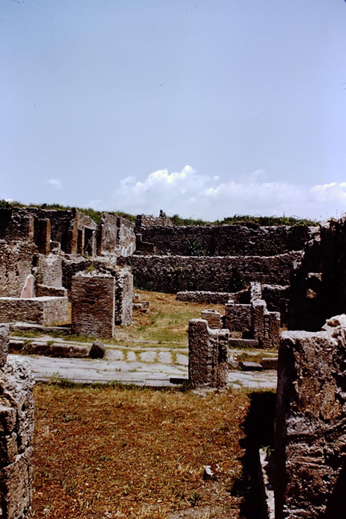 I.1.8 Pompeii. September 2010. Entrance doorway, looking east from Via Stabiana.
The entrance for I.1.7 is on the right side of the entrance). Photo courtesy of Drew Baker.

According to Warscher, quoting Mau in Bull.Inst 1875, p.30, I.1.6-9: “Segue un altro albergo, molto simile a questo descritto.  Qui pure è interrotto il marciapiede per lasciar entrare i legni. L’entrata era chiuse mediante una porta a quattro partiti, congiunti a due adue, come si conosce dai quattro buchi per i chiavistelli.  Qui pure si entra prima in un compreso che ha le dimensioni d’una bottega grande con una dietrobottega e posteriormente si apre sopra una grande corte, lungo il cui muro di fondo qui pure si stende la stalla, larga 13,30, profonda 2,47 con una finestra sul vico settentrionale e due porte, una all’estremità meridionale, l’altra poco distante da quella settentrionale. 
Presso a quest’ultima una parte della corte è selciata.  Lungo il muro N vi sono due camere con finestre sul medesimo vico, e prossimo alla stalla il cesso. Si vede anche il cesso del piano superiore e i tubi di mattone d’un terzo, che stava ancora più in alto.  
Nell’angolo NO vi sono I primi gradini d’una scala, la cui parte superiore sarà stata di legno, in quello SO l’apertura della cisterna, e accanto nella stessa massa di materiale una vasca lunga stretta e bassa, come quella sudescritta nella casa adiacente. Qui la vediamo frapposto fra la cisterna ed il muro di O, il che esclude categoricamente l’aver essa servito d’abbeveratoio. Dalla parte più bassa di essa, aperta come nella casa sudescritta, l’acqua colava in un’altra vasca larga 1,02 x 1,54, di cui un lato viene formato dalla suddetta massa di fabbrica, uno dal muro occidentale, i due rimanenti da appositi muricciuoli.  Essa ha al fondo uno scolo verso N, che dà in un vaso ossia tubo di mattone, incastrato nel suolo. Nella parete vi era la pittura dei Lari, di cui sono rimasti soltanto i serpi. A destra dell’ingresso per i legni sta un locale come una bottega. 
L’essere esso congiunto mediante una porta con quel primo compreso, ove entravano i legni, ci lascia supporre, aver esso servito di caupona per i vetturini”.
See Warscher T., 1935. Codex Topographicus Pompeianus: Regio I.1/I.5. Rome: DAIR. (no.14)
(for a translation see, I.1.6).