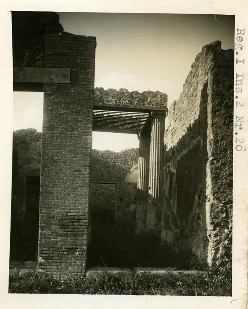 I.2.28 Pompeii. 1935 photo taken by Tatiana Warscher. Looking north to entrance doorway, and west side of entrance corridor.
See Warscher T., 1935. Codex Topographicus Pompeianus: Regio I.2. (no.50), Rome: DAIR, whose copyright it remains.
Warcher wrote –  I.2.28/29 “La casa no.28 presenta un interesse speciale. La prima cosa – un atrio tetrastilo con un impluvio difeso da inferriata.  Poi il triclinio a mattoni (h) costruito sopra uno sotterraneo; infine un piccolo forno (k). Quanto alla pittura – non c’è rimaste niente sul posto. Dal triclinio (i) è stata tolta la pittura di Cassandra e d’un bel paesaggio non si vedono che le traccie deboli.”
(translation: House number 28 presents a special interest. Firstly a tetrastyle atrium with an impluvium guarded with an iron grating. Then the masonry triclinium (h) constructed above an underground area.  Finally, a small oven (k). As for the paintings, nothing remains in situ.
The painting of Cassandra has been removed from the triclinium, and only the ruined traces of a beautiful landscape could be seen.” (Note: the numbers in brackets refer to Warscher’s plan with room numbers).
