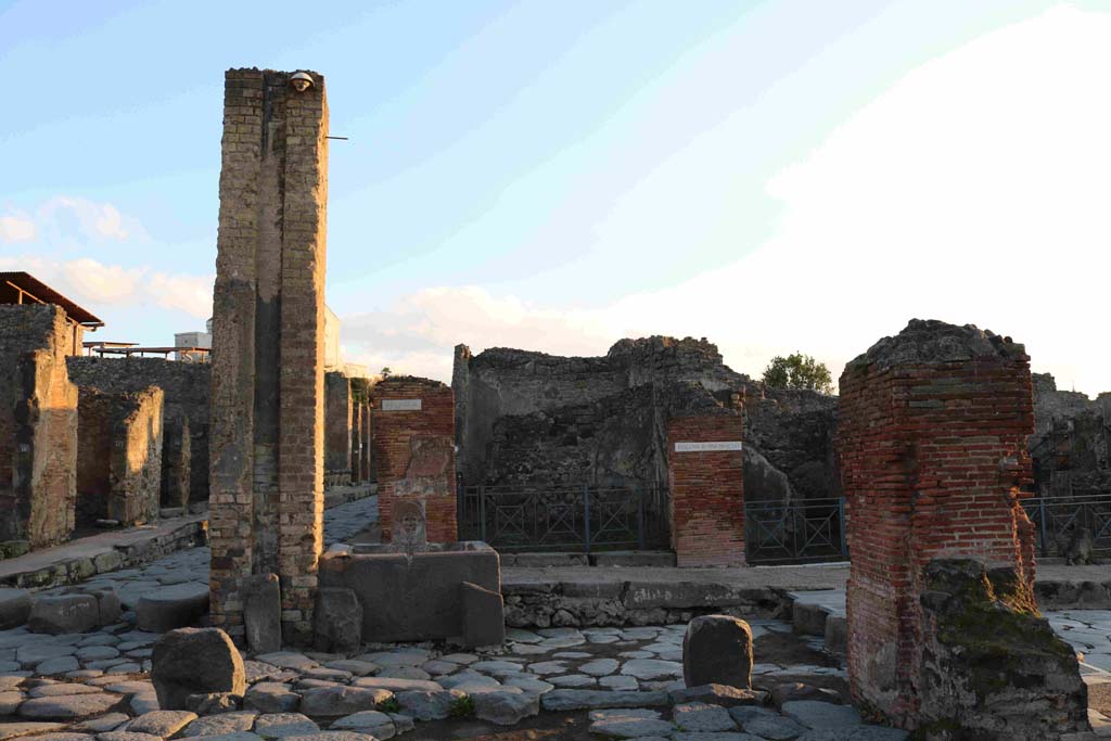I.4.15 Pompeii. December 2018. Looking east across Holconius’ crossroads on Via Stabiana, towards I.4.15 behind fountain at south-east corner of crossroads. 
Photo courtesy of Aude Durand.
