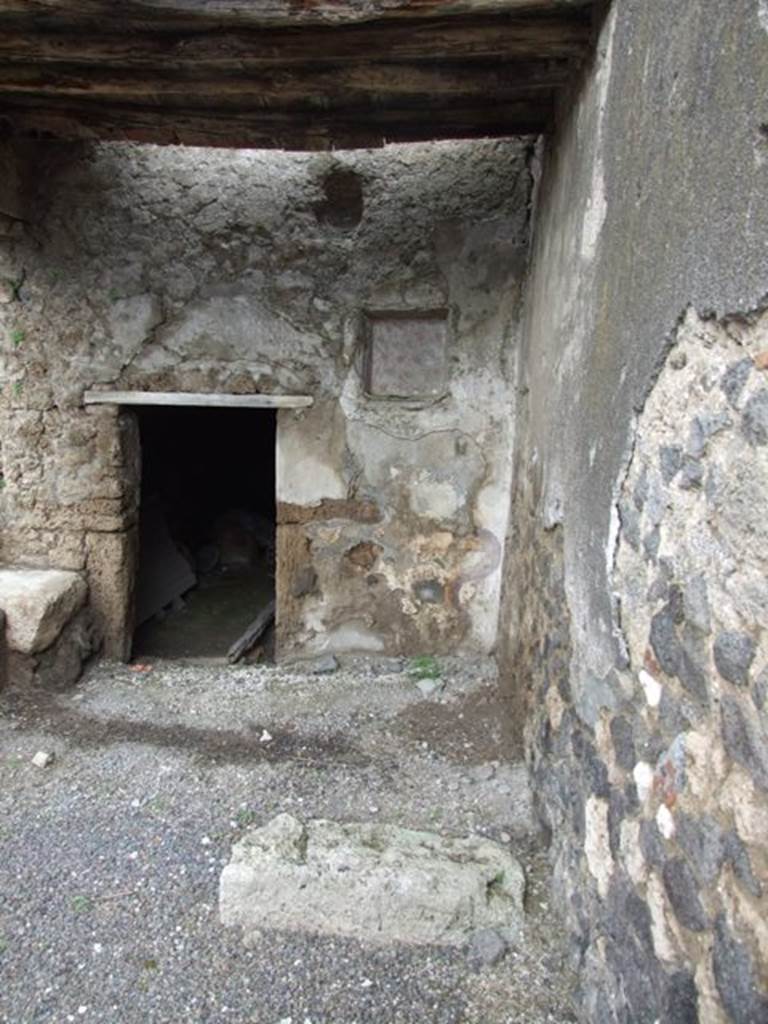 I.8.10 Pompeii. March 2009. Area on north-east of peristyle. Doorway to underground kitchen with a latrine, and niche on north wall. According to Jashemski, on both sides of the door leading to the basement room was a Lararium. The one on the left was already destroyed at the time of its discovery (the excavations started in the years immediately preceding World War II, were suspended in 1941, and were completed around the beginning of the 1950’s). The one on the right was well preserved, with painting of serpents, altar and 2 Lares, now however, less visible. The niche is decorated with flowers that have the appearance of poppies.
See Jashemski, W. F., 1993. The Gardens of Pompeii, Volume II: Appendices. New York: Caratzas. (p.42)

