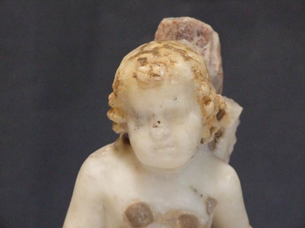 I.9.14 Pompeii.  Marble fountain statuette.  Amorino with basket on arm riding on dolphin.  Head of Amorini.  SAP inventory number 8127.  Found in 1951.