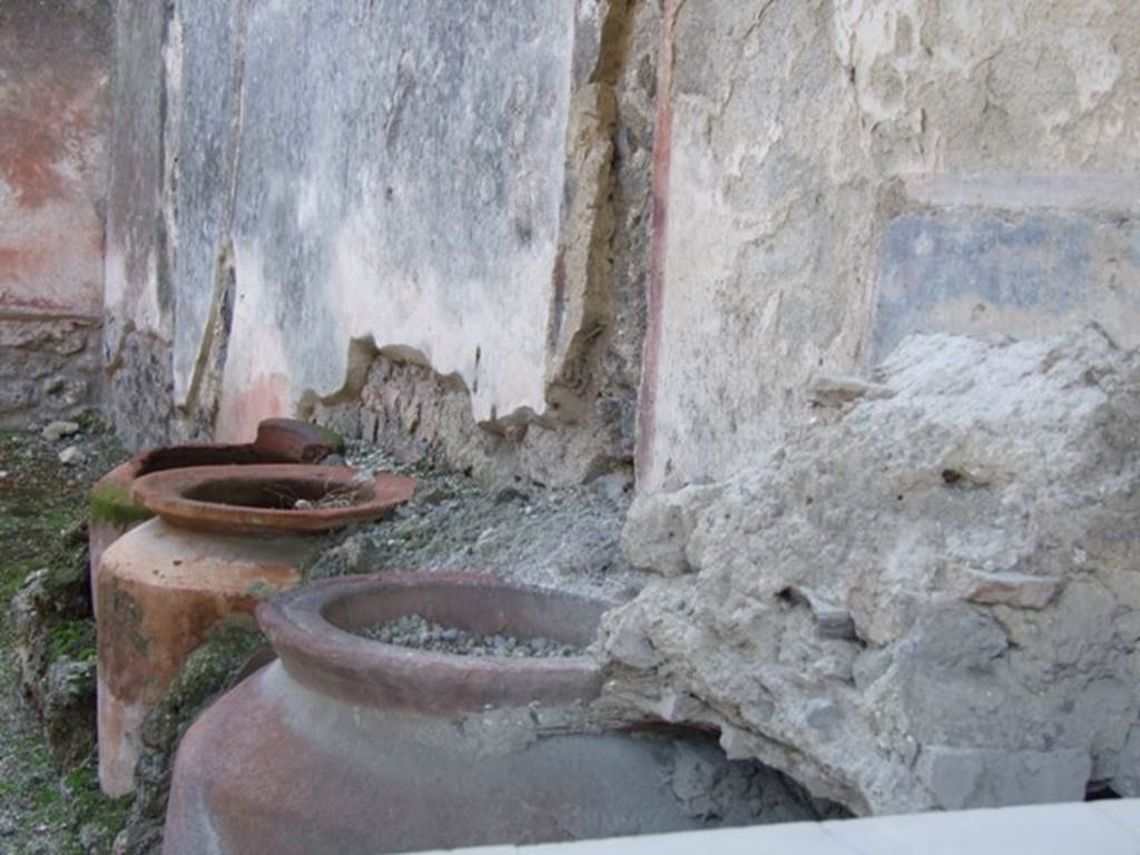 I.11.1 Pompeii.  Caupona.  West side.  Remains of four urns and shelves for displaying drinking vessels.