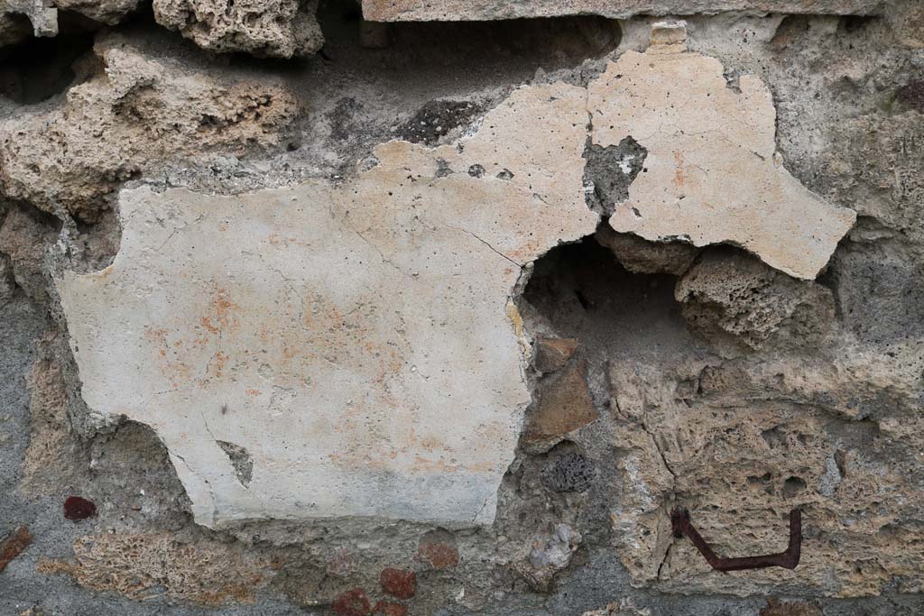 I.11.10 Pompeii. December 2018. Detail of remaining stucco below lararium in east wall. Photo courtesy of Aude Durand.