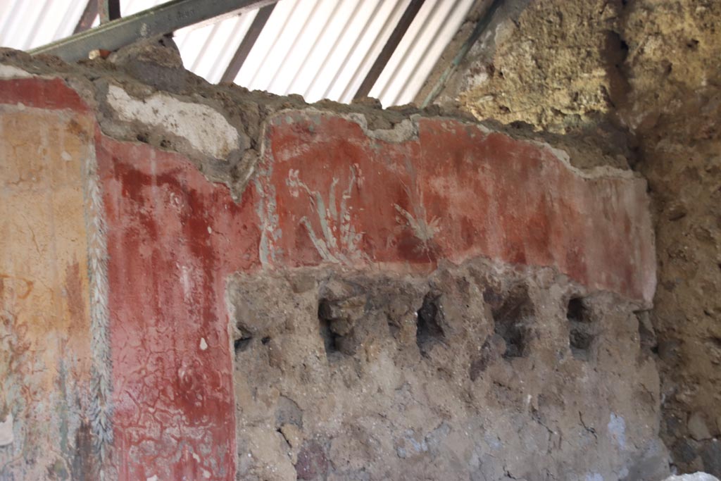 I.12.8 Pompeii. October 2022. 
Peristyle 9, north wall at east end, detail of painted wall above holes for supports of ceiling above latrine 12. Photo courtesy of Klaus Heese.
