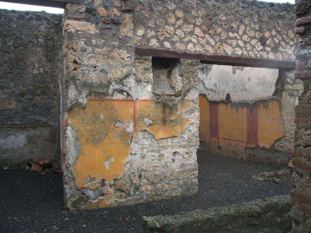 I.13.11 Pompeii. December 2004. Looking west across garden area.
Doorways to cubiculum on left, and oecus on the right, on west side of garden, with lararium niche between. According to PPP, on the west wall between doorways was the lararium niche, with serpent, red flowers and red border, much decayed. See Bragantini, de Vos, Badoni, 1981. Pitture e Pavimenti di Pompei, Parte 1. Rome: ICCD. (p.189)
According to Frhlich and Giacobello, the rectangular niche was painted on its inside walls with red flowers, no longer conserved.  There may have been two statuettes found in this lararium, Hercules and Minerva.
See Frhlich, T., 1991. Lararien und Fassadenbilder in den Vesuvstdten. Mainz: von Zabern. (L31)
See Giacobello, F., 2008. Larari Pompeiani: Iconografia e culto dei Lari in ambito domestico.  Milano: LED Edizioni. (p.233)
According to PPM, the lower yellow zoccolo was divided into two panels by a vertical red band. On the south end was a painted vignette showing two doves with cherries, and at the north end under the niche was the painted lararium showing two serpents approaching a central altar with eggs.
See Carratelli, G. P., 1990-2003. Pompei: Pitture e Mosaici. Vol.II  Roma: Istituto della enciclopedia italiana. (p.916).


