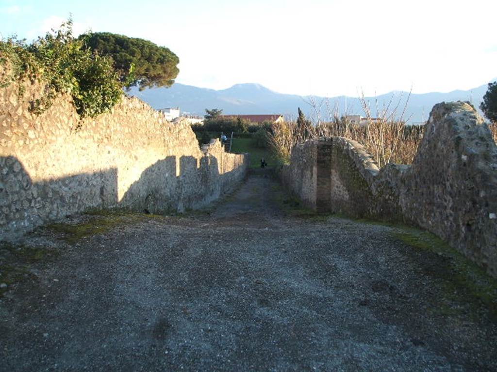 I.21 Pompeii. December 2004.  Roadway looking south.   Side wall of  I.22.3
