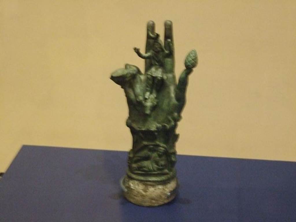 II.1.12 Pompeii. Bronze hand of Sabazius. SAP 10486. 
Photographed at “A Day in Pompeii” exhibition at Melbourne Museum. September 2009.  According to Berry, SAP 10486 was one of two similar votive hands found in a shrine at the house at II.1.12. Sabazius was sitting in the centre of the palm with his arms raised in benediction. Around the hand are a snake, a caduceus, a knife, a scale and a woman with child.According to Berry, Sabazius was often equated with Zeus or Dionysus. See Berry, J., 2007. The Complete Pompeii. London, Thames & Hudson, (p.200-1). See Conticello, B., Ed, 1990. Rediscovering Pompeii. Rome: L’Erma di Bretschneider. (p.138-139). Both hands, inventory numbers SAP 10485 and 10486 can be seen in Cibi e Sapori a Pompei e Dintorni, (p.37). See Cicirelli, C. (2005): Religio: feste e rituali del culto pubblico e privato, (p.20-38) in the above book.
